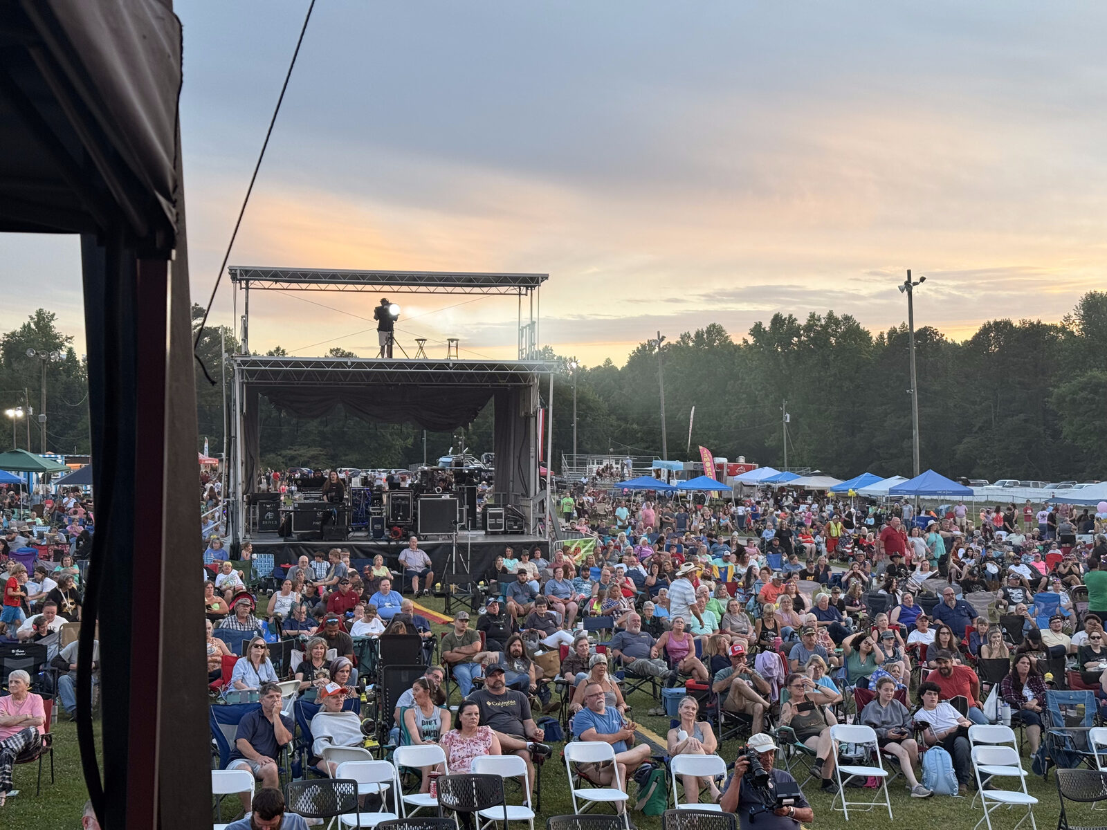 Outdoor festival mainstage with packed crowd at sunset